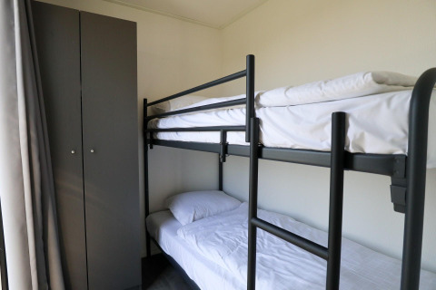 Modernes Etagenbett und Kleiderschrank in einem kleinen Raum im Cube Exclusive Plus, EuroParcs Bad Meersee, Niederlande.