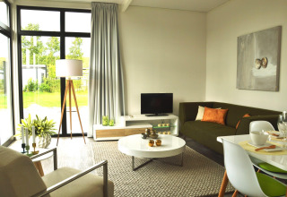 Moderne woonkamer in het Cube tiny house op EuroParcs Bad Meersee, Nederland, met veel licht en sofa.
