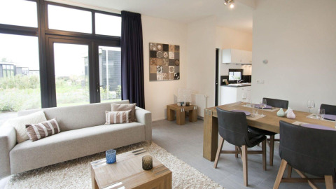 Moderne woonkamer en eethoek in tiny house Cube La Mer 4 bij EuroParcs Bad Meersee, Nederland, met veel licht.