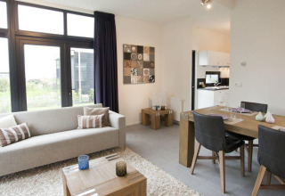 Moderne woonkamer en eethoek in tiny house Cube La Mer 4 bij EuroParcs Bad Meersee, Nederland, met veel licht.