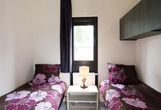 Slaapkamer met twee eenpersoonsbedden, bloembeddengoed, lamp en raam in Cube La Mer 4, EuroParcs.