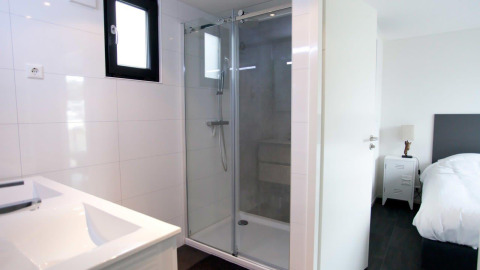 Modern bathroom with walk-in shower and bedroom view in Cube Exclusive 4 tiny house at EuroParcs Bad Meersee.