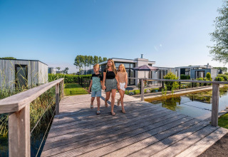 Family walking on a wooden bridge near Cube Exclusive 4 tiny house at EuroParcs Bad Meersee, Netherlands.