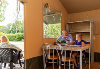 Älterer Mann und Junge genießen gemeinsame Zeit im Safarizelt im De Tien Heugten, Niederlande.