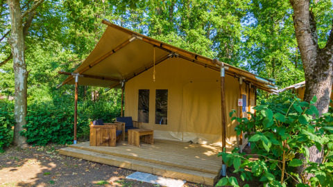 Safari tent genaamd Slow lodge met 2 slaapkamers, houten terras en tuinmeubilair in bosrijke omgeving.