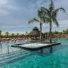 Large swimming pool with palm trees and sunbeds at La Marina Resort - Lodges Alicante on a sunny day.