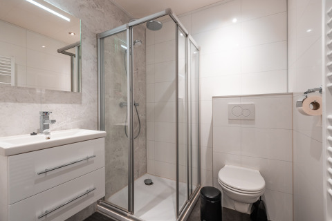 Bagno moderno con cabina doccia, WC sospeso e lavabo presso Zandborg Lodge a De Wiltzangh, Paesi Bassi.
