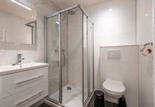 Bagno moderno con cabina doccia, WC sospeso e lavabo presso Zandborg Lodge a De Wiltzangh, Paesi Bassi.