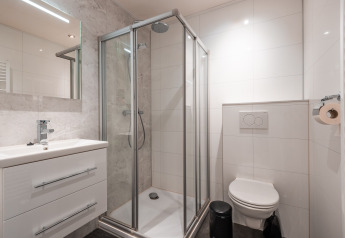 Modern bathroom with shower cabin, wall-mounted toilet, and sink at Zandborg Lodge in De Wiltzangh, Netherlands.