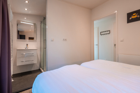 Bedroom at Zandborg Lodge in Holiday park De Wiltzangh, Netherlands, with double bed and ensuite bathroom.