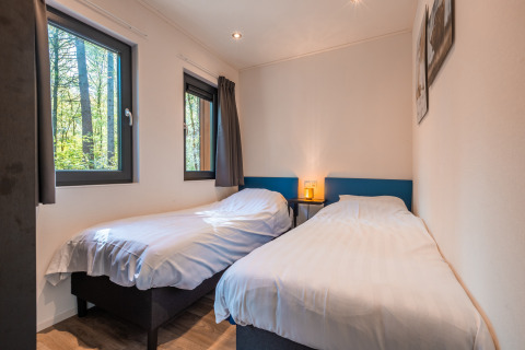 Camera luminosa con due letti singoli, grandi finestre e arredamento moderno presso Zandborg Lodge, De Wiltzangh.