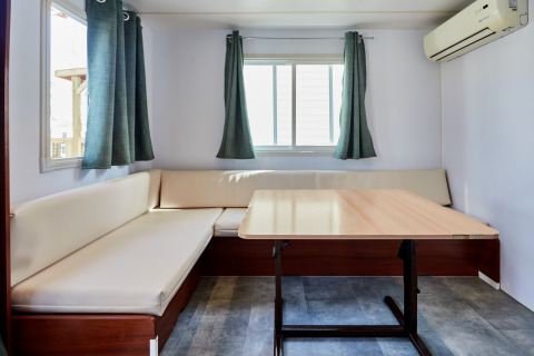 Salón luminoso del Bungalow Essential Flamenc, TAIGA Delta de l'Ebre, España, con sofá, mesa y aire acondicionado.