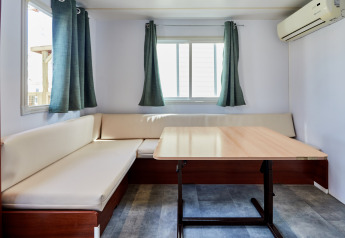 Salón luminoso del Bungalow Essential Flamenc, TAIGA Delta de l'Ebre, España, con sofá, mesa y aire acondicionado.