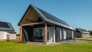 Udendørs billede af Duinlodge 6 med moderne sort facade, terrasse og solpaneler på taget.