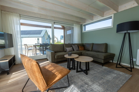 Stue i Duinlodge 6 på EuroParcs Cadzand-Bad, Holland, med sofa, moderne møbler og stort vindue.