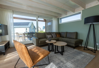 Stue i Duinlodge 6 på EuroParcs Cadzand-Bad, Holland, med sofa, moderne møbler og stort vindue.
