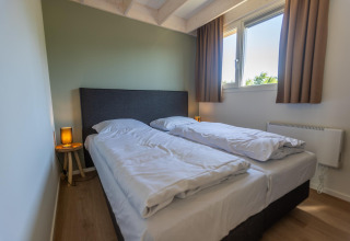 Moderne soveværelse med to enkeltsenge, store vinduer og naturligt lys i Duinlodge 6, EuroParcs Cadzand-Bad.