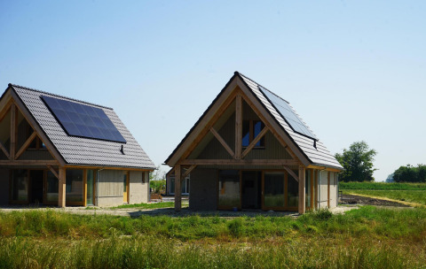 Twee moderne houten lodges met zonnepanelen op het dak bij Duinvilla 10, omgeven door groen landschap.