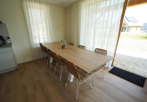 Eethoek in lodge «Duinvilla» 10 bij EuroParcs Cadzand-Bad, Nederland, met grote houten tafel en stoelen.