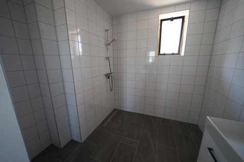 Badkamer met douche, witte wandtegels en grijze vloertegels in Duinvilla 10, EuroParcs Cadzand-Bad.