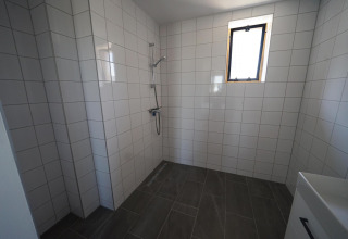 Badkamer met douche, witte wandtegels en grijze vloertegels in Duinvilla 10, EuroParcs Cadzand-Bad.