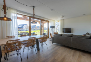 Soggiorno moderno e zona pranzo nella Duinvilla 8 di EuroParcs Cadzand-Bad, con ampie finestre panoramiche.