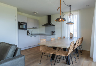 Cucina e sala da pranzo moderne in Duinvilla 8 a EuroParcs Cadzand-Bad, Paesi Bassi, con arredi chiari.