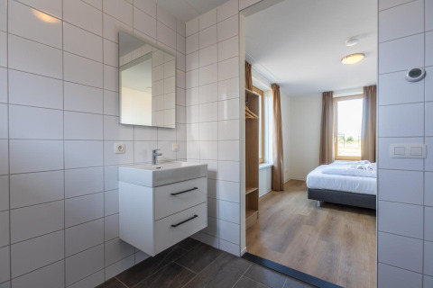 Bagno moderno con piastrelle bianche e vista sulla camera da letto a Duinvilla 8, EuroParcs Cadzand-Bad, Paesi Bassi.