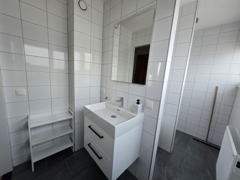 Bagno moderno in una lodge con piastrelle bianche, lavabo doppio, specchio e scaffale semplice.