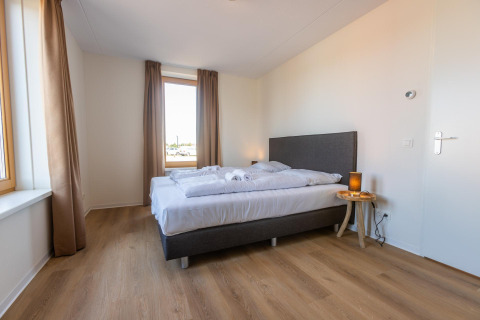 Camera da letto moderna con letto matrimoniale, parquet e finestra grande a Duinvilla 8, EuroParcs Cadzand-Bad.