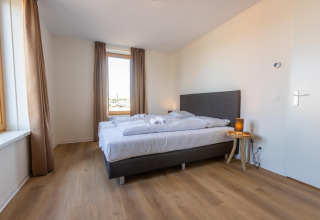 Camera da letto moderna con letto matrimoniale, parquet e finestra grande a Duinvilla 8, EuroParcs Cadzand-Bad.