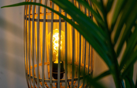 Close-up van een brandende lamp in een houten lampenkap bij Pavilion-lodge, EuroParcs Texel, Nederland.