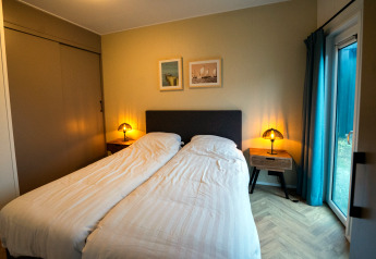 Accogliente camera in un lodge con due letti singoli, comodini, lampade e accesso alla terrazza.