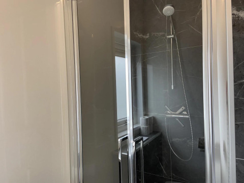 Moderne douche met glazen deuren en donkere tegels in een Pavilion lodge-badkamer bij EuroParcs Texel.