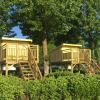 Two wooden glamping lodges on stilts at Camping Le Lac des Sapins – Lodges Auvergne Rhône Alpes surrounded by trees.