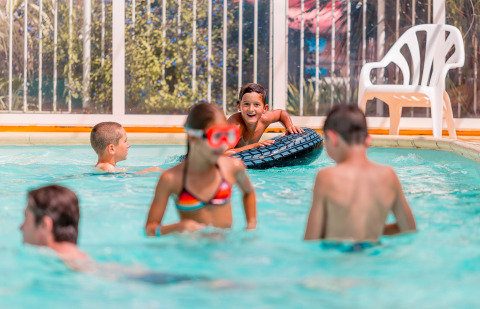 Bambini che giocano e nuotano in una piscina coperta al Flower Camping La Pointe du Talud in Bretagna, Francia.