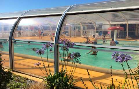 Piscina cubierta con familias disfrutando en Flower Camping La Pointe du Talud, en Bretaña, Francia.