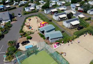 Vue aérienne de Flower Camping La Pointe du Talud en Bretagne avec mobil-homes, aire de jeux et terrain de sport.