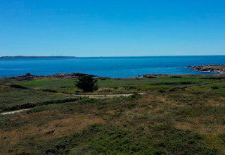Coastal scenery at Flower Camping La Pointe du Talud, Brittany, France, with clear blue skies and sea.