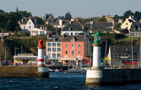 Coastal town near Ploemeur in Brittany, France, showing colorful houses, marina, and two lighthouses by water.