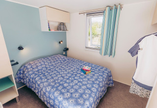 Camera da letto nella casa mobile Comfort BAHIA al Flower Camping La Pointe du Talud in Francia, letto blu.