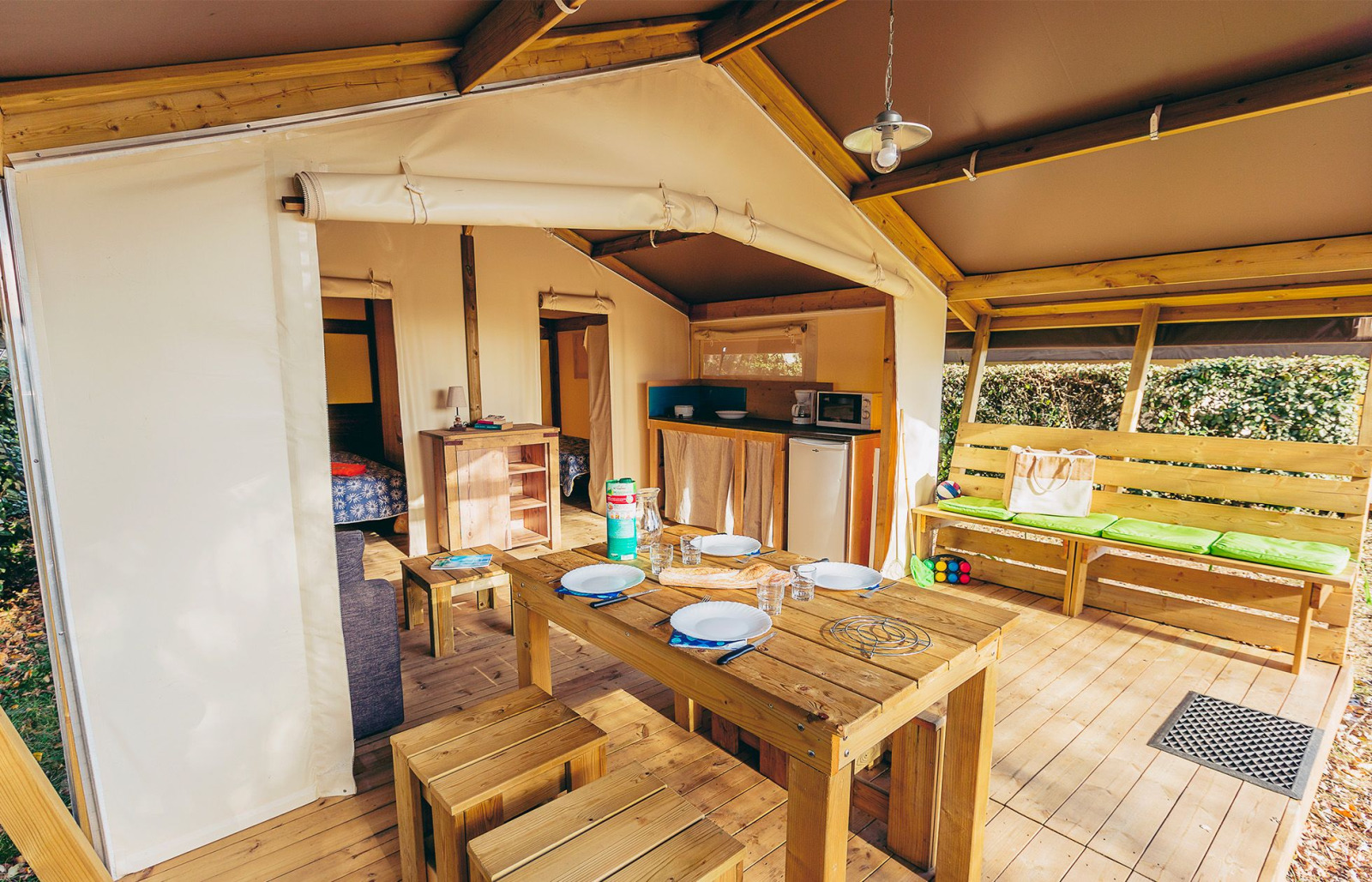 Interieur van een safaritent met houten eettafel, keuken en bank bij La Pointe du Talud in Frankrijk.