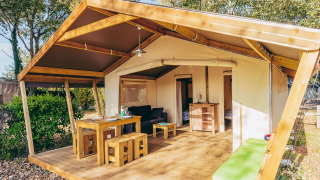 Safari tent Free Flower Standard featuring wooden terrace, open living space, picnic table, and outdoor charm.
