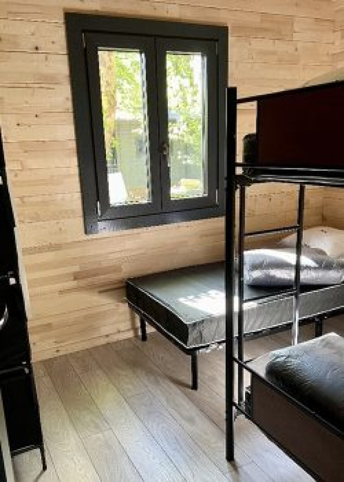 Kamer met stapelbedden en een raam in het Chalet op Camping La Grande Véyière in Frankrijk, houten wanden.