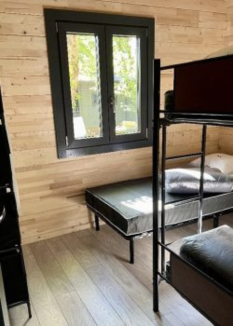 Kamer met stapelbedden en een raam in het Chalet op Camping La Grande Véyière in Frankrijk, houten wanden.