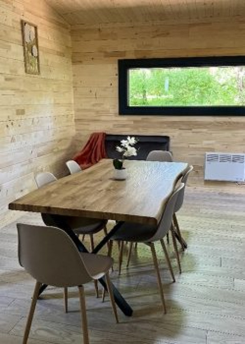 Zona pranzo nello Chalet al Campeggio La Grande Véyière, Francia, con interni in legno e grande finestra.