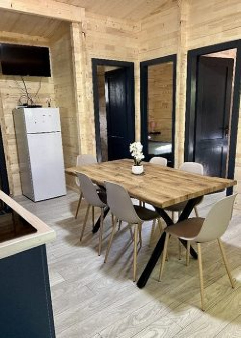 Eethoek in een chalet op camping La Grande Véyière, Frankrijk, met houten tafel, zes stoelen, koelkast en tv.