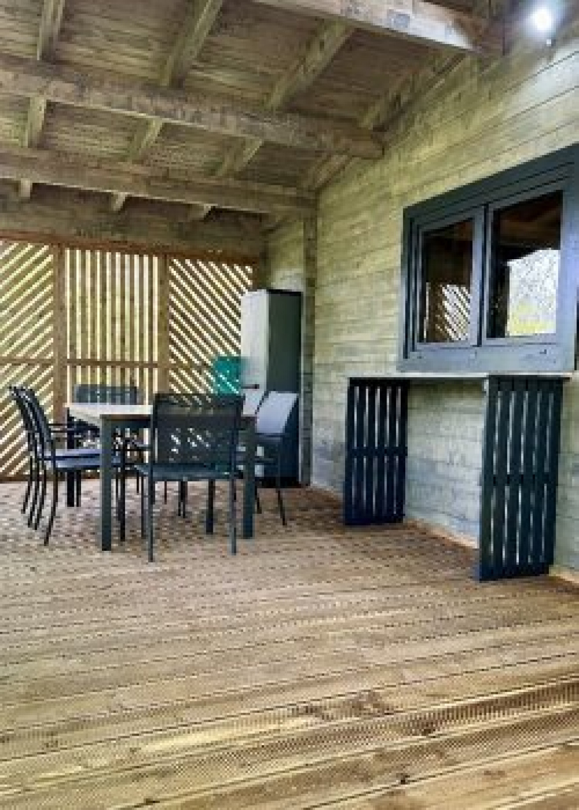 Overdekt houten terras met eettafel en stoelen bij Chalet op Camping La Grande Véyière in Frankrijk.