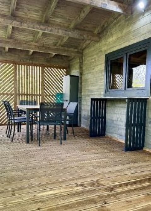 Overdekt houten terras met eettafel en stoelen bij Chalet op Camping La Grande Véyière in Frankrijk.