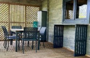 Terrazza in legno coperta con tavolo e sedie al Chalet del Campeggio La Grande Véyière in Francia.